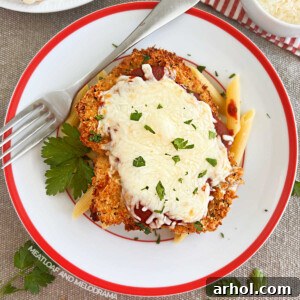 baked chicken Parmesan with penne pasta on a red and white plate