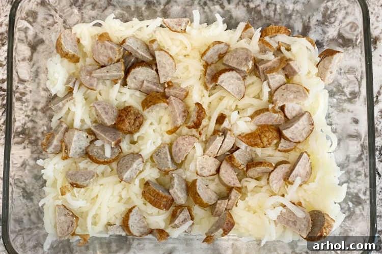 shredded hash brown potatoes and sliced breakfast sausage in a baking dish