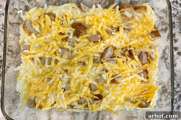hash brown potatoes, sausage slices and shredded cheese in a casserole dish