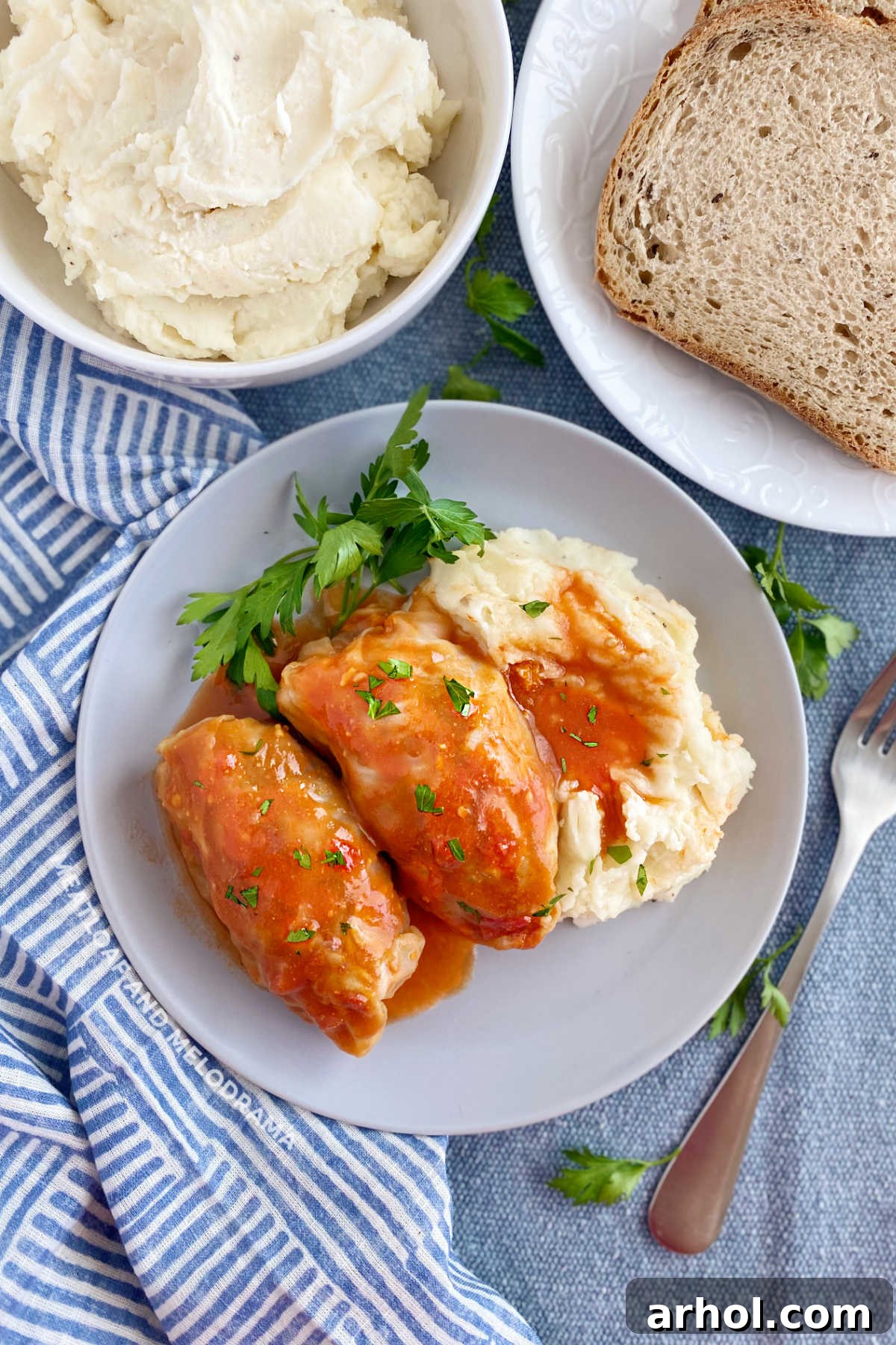 Grandma's cabbage rolls in tomato soup sauce with mashed potatoes and rye bread on the table, showcasing a full, hearty meal.