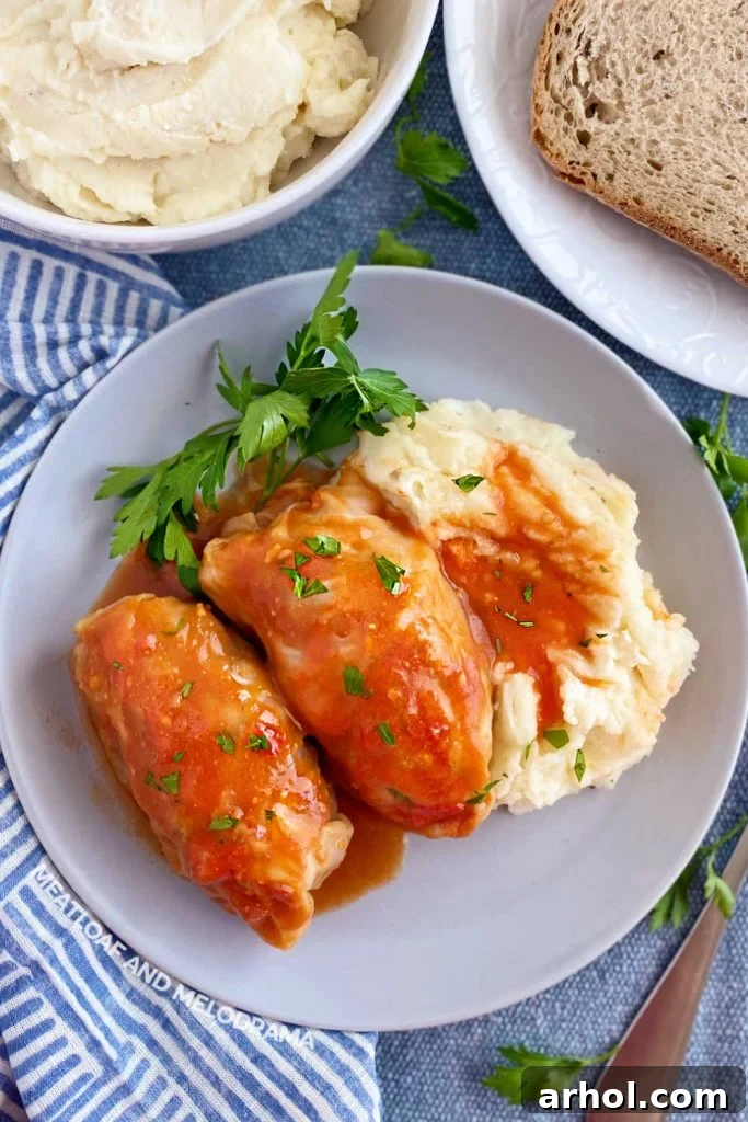 stuffed cabbage rolls in tomato soup sauce with mashed potatoes on a white plate, ready to be enjoyed.