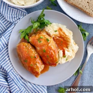 2 cabbage rolls (slovak halupki) in tomato soup sauce with mashed potatoes on plate