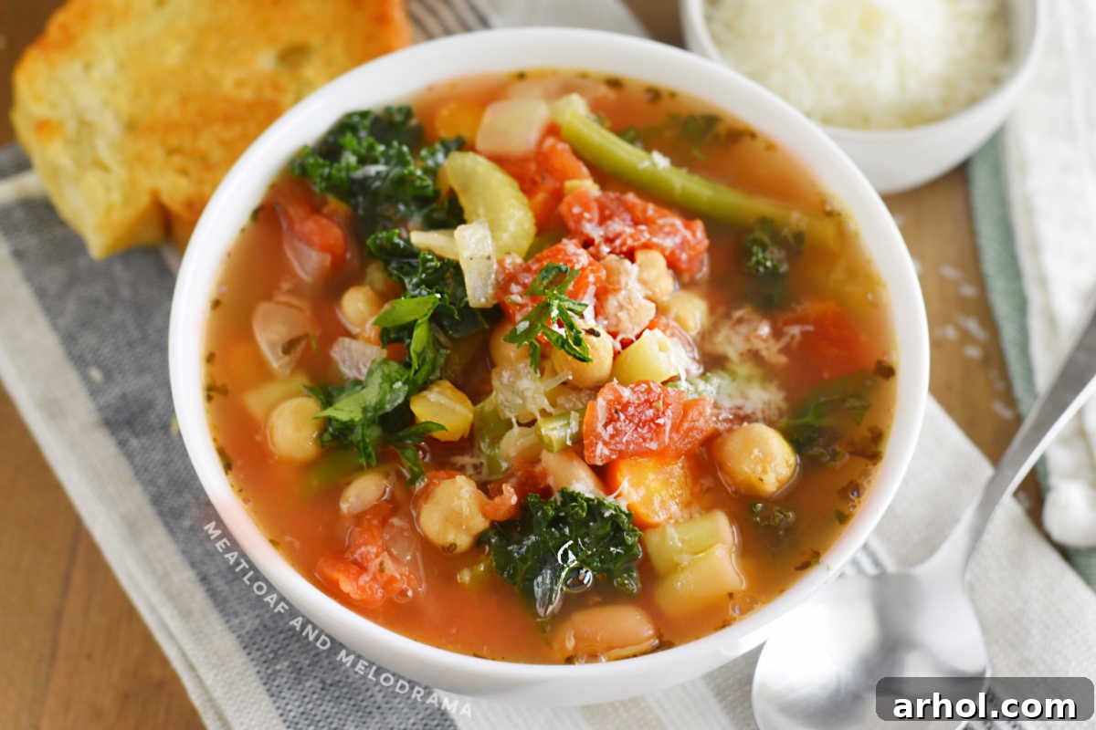 A vibrant bowl of Instant Pot Minestrone Soup, garnished with fresh parsley and served alongside crusty garlic bread and grated Parmesan cheese.
