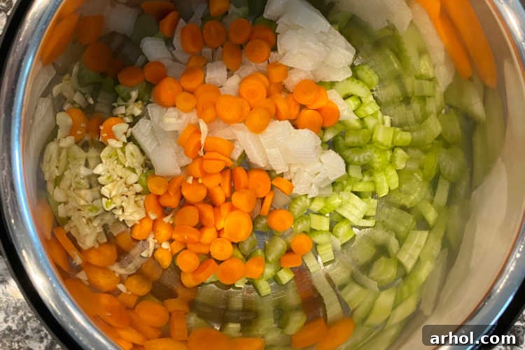 Chopped carrots, onions, celery, and garlic sizzling in olive oil inside the Instant Pot.