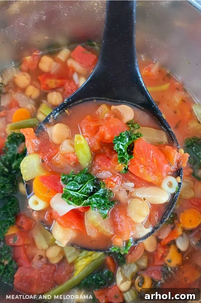 A ladle scooping hot Minestrone Soup from the Instant Pot, showcasing the rich tomato broth and various vegetables.