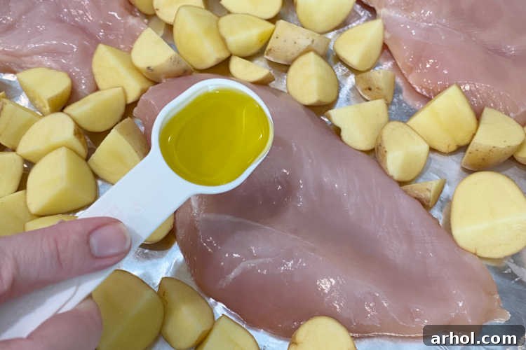 Effortless Ranch Chicken Sheet Pan 3 Pour olive oil over chicken breasts and potatoes on a sheet pan for an easy ranch dinner.