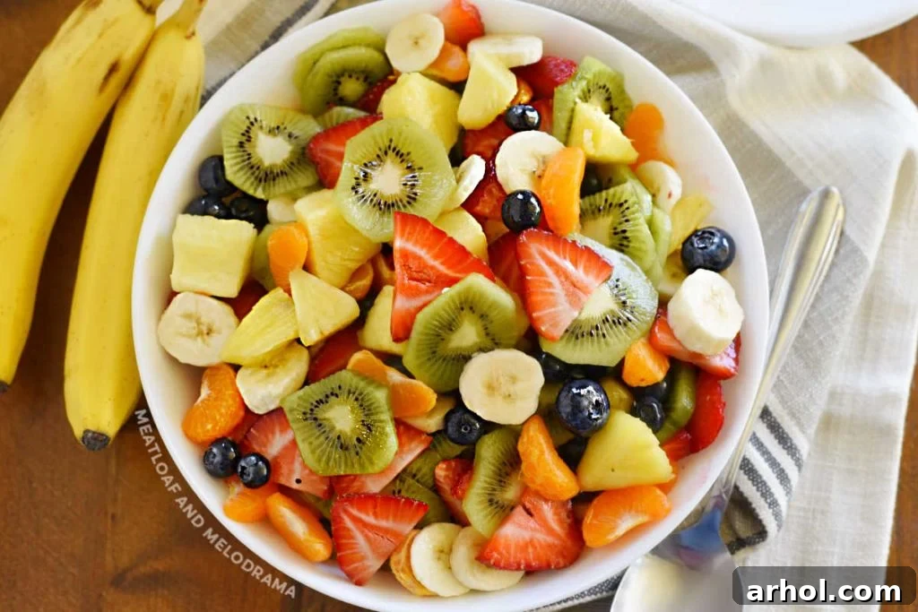 A beautiful summer fruit salad arranged appealingly in a white serving bowl, ready to be enjoyed as a refreshing healthy side dish for cookouts or any summer gathering.