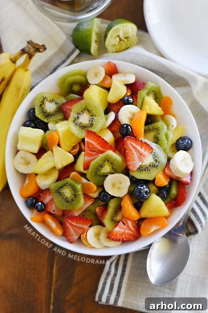 A vibrant assortment of cut-up summer fruits artfully arranged in a pristine white serving bowl, showcasing nature's colorful bounty, perfect for a healthy gathering.