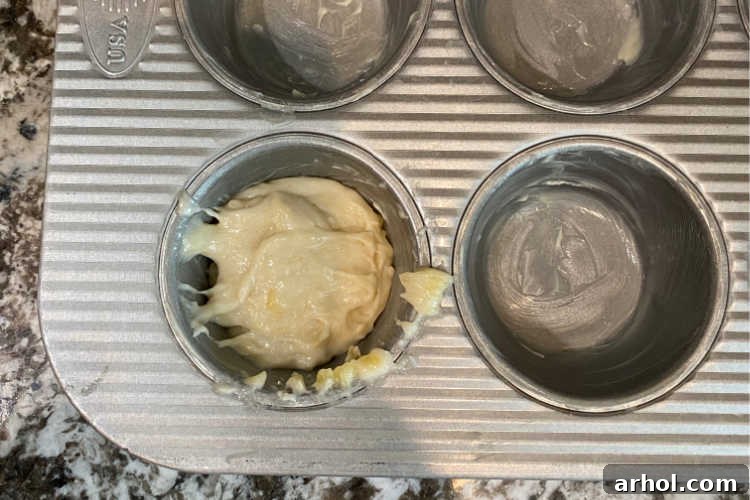 Scooping two-ingredient banana muffin batter into a prepared muffin tin