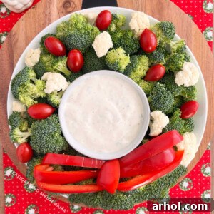 christmas wreath vegetable platter made with broccoli, cauliflower, tomatoes and red pepper strips with dip