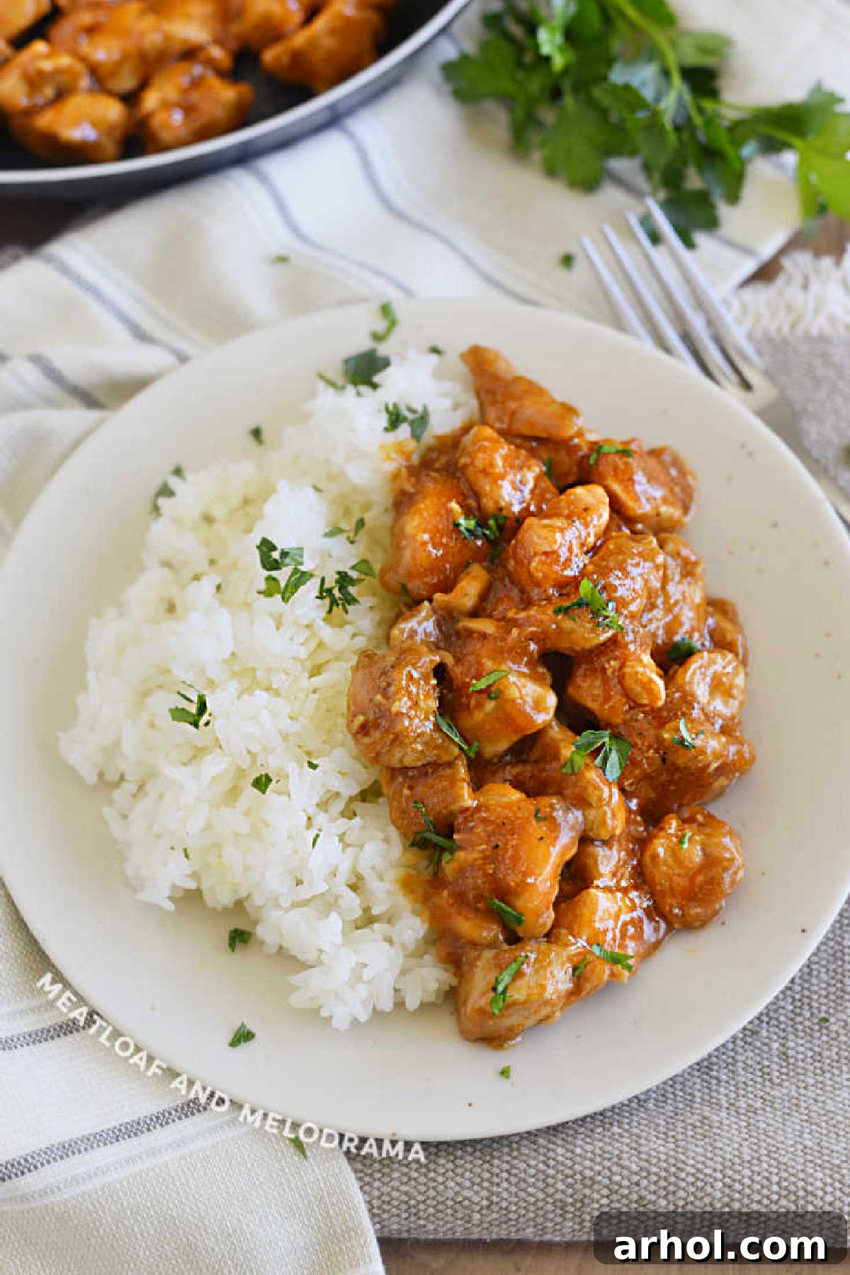 Plate of golden-brown Bourbon Street chicken pieces with fluffy jasmine rice, garnished with fresh parsley.