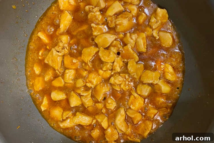 Cubed chicken simmering beautifully in a rich bourbon sauce.