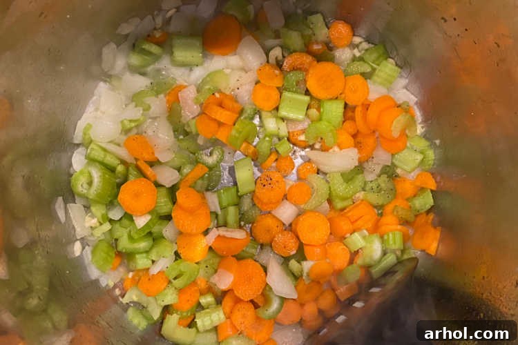 Chopped onions, carrots, and celery sautéing in butter in the Instant Pot liner, emitting a fragrant aroma.
