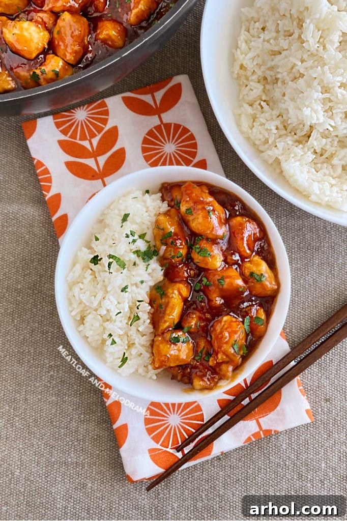 Effortless Zesty Orange Chicken 2 Crispy orange chicken and fluffy jasmine rice in a white bowl, ready to eat with chopsticks