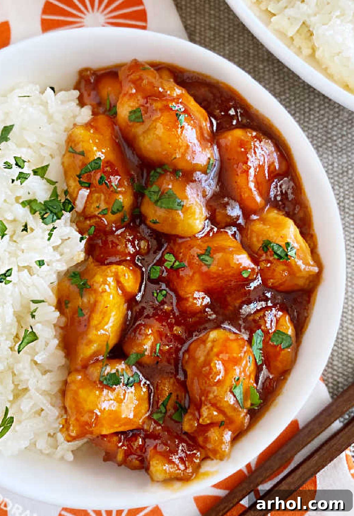 Effortless Zesty Orange Chicken 3 Close-up of golden brown orange chicken in a glossy 3-ingredient sauce, served with steamed jasmine rice