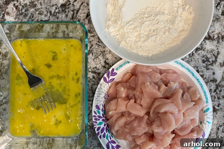 Effortless Zesty Orange Chicken 4 Cubed boneless skinless chicken breasts, beaten eggs, and all-purpose flour laid out on a kitchen counter, ready for coating