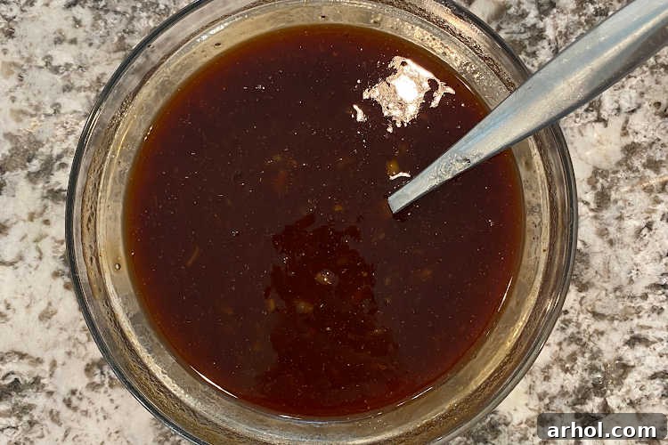 Effortless Zesty Orange Chicken 6 Orange marmalade, BBQ sauce, and soy sauce in a mixing bowl, being whisked together to create the signature 3-ingredient orange chicken sauce