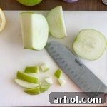 Close-up of freshly chopped green apples on a cutting board, ready to be added to the chicken salad.