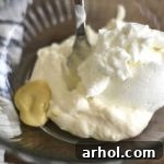 A creamy chicken salad dressing being mixed in a bowl, featuring mayonnaise, Greek yogurt, and Dijon mustard, showing the smooth texture before other ingredients are added.