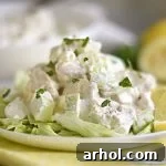 A serving of lemon chicken salad with apples arranged on a bed of fresh lettuce on a white plate, showcasing the final delicious presentation.