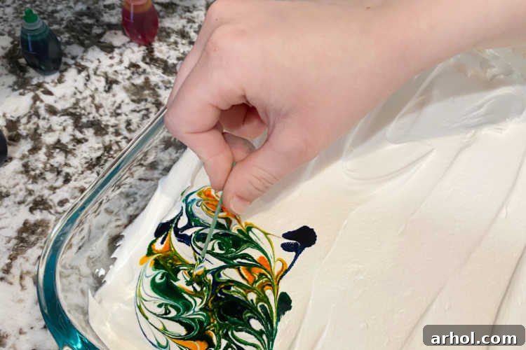A toothpick is gently used to swirl food coloring into the whipped topping, creating intricate marble patterns.