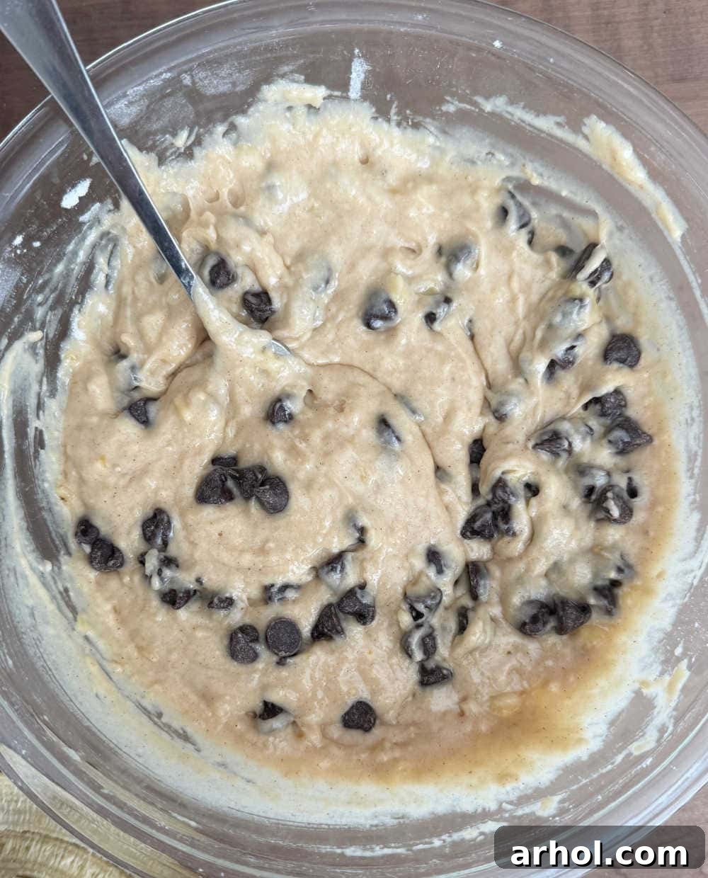 Semi-sweet chocolate chips being gently folded into the banana muffin batter.