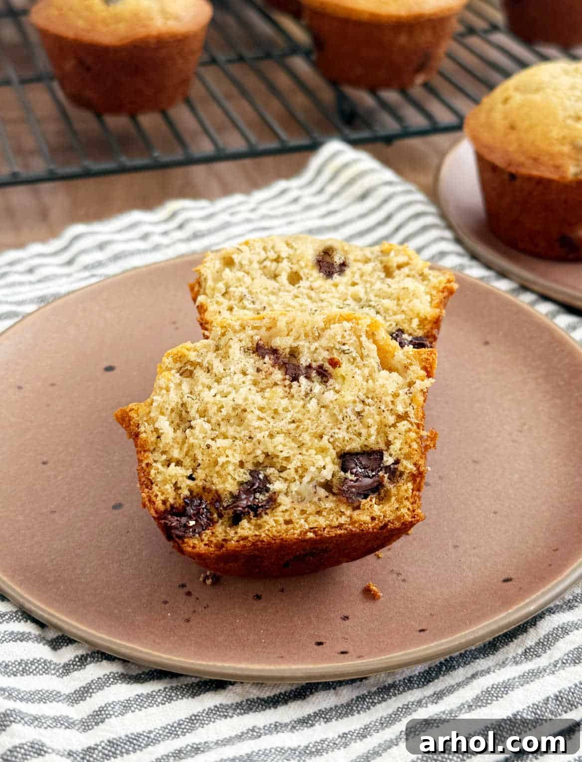 A perfectly sliced banana muffin, revealing its moist interior and a generous scattering of chocolate chips, served on a plate.