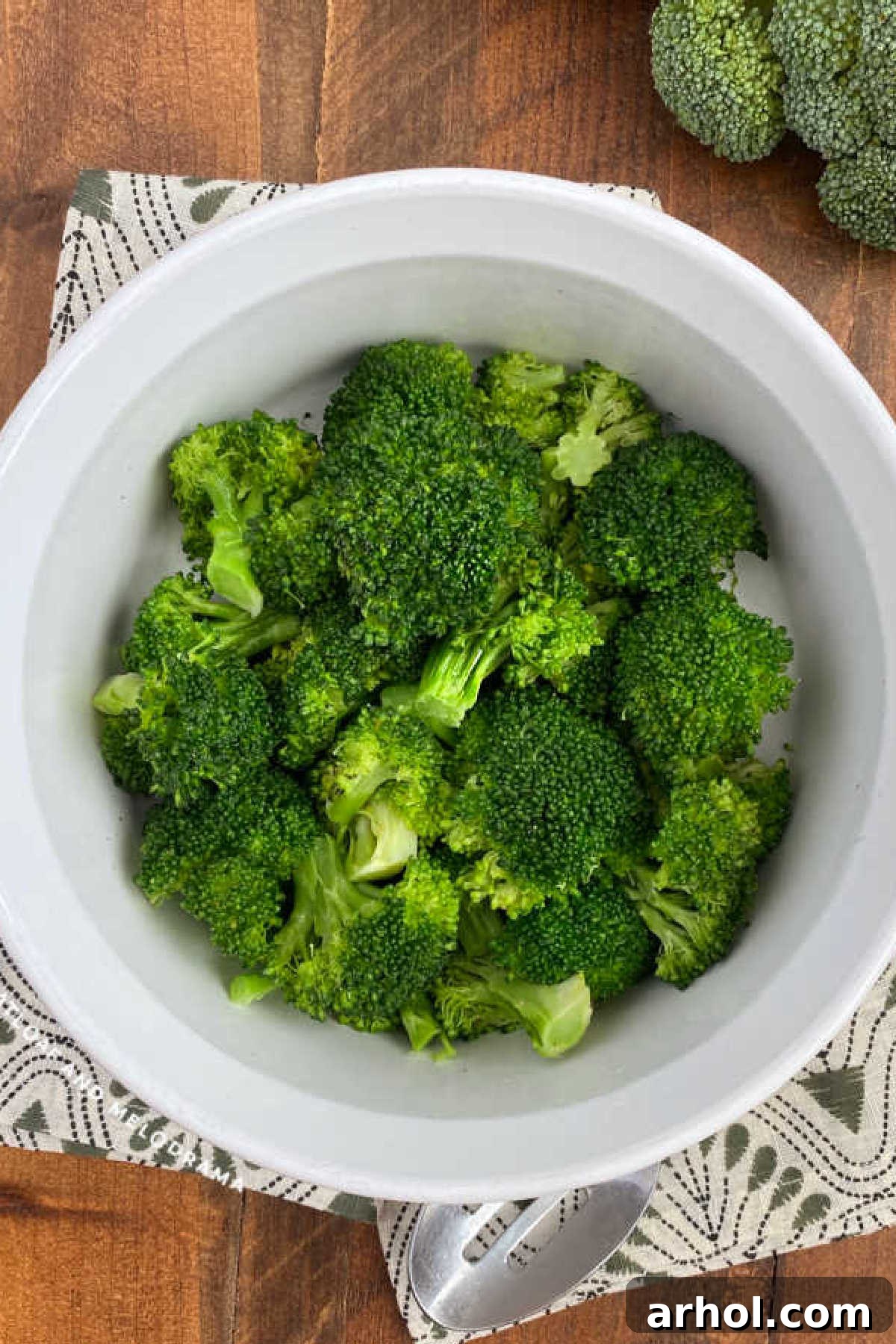 Steamed microwave broccoli in a white serving dish, garnished