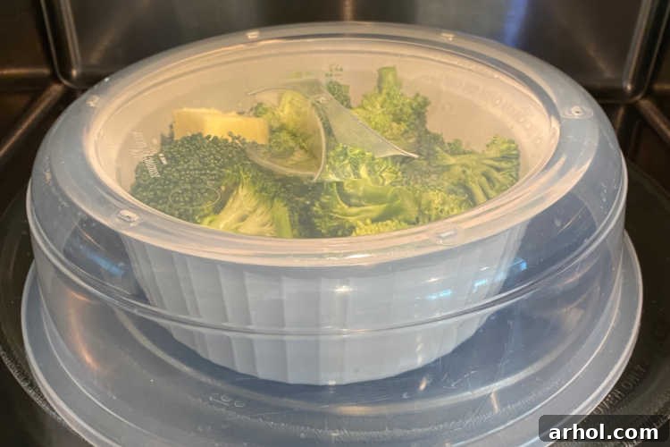 Microwave-safe bowl of broccoli covered and ready for cooking