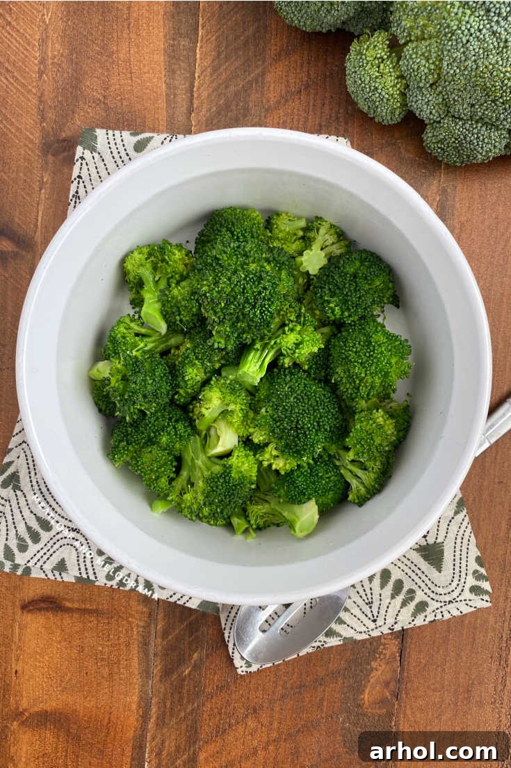 Cooked steamed broccoli in a white serving bowl on a wooden table