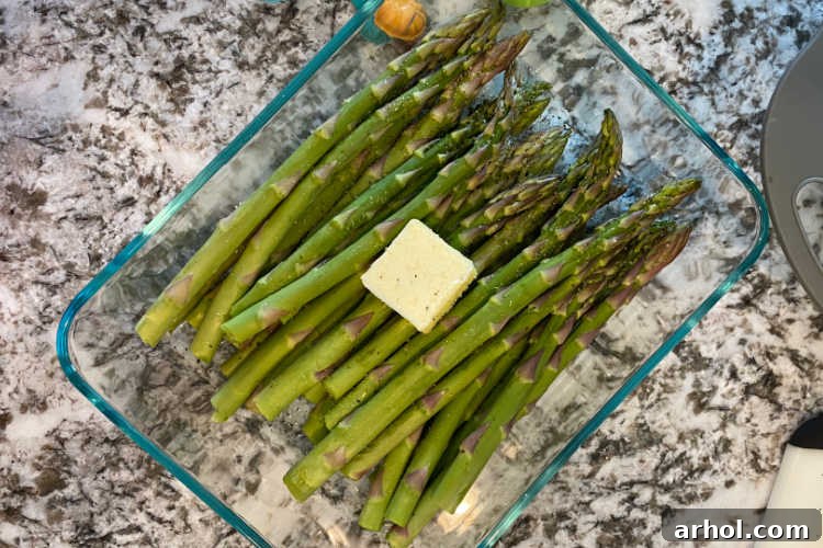 raw asparagus with butter in glass baking dish