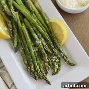 microwave asparagus on white platter with lemon slices and parmesan cheese
