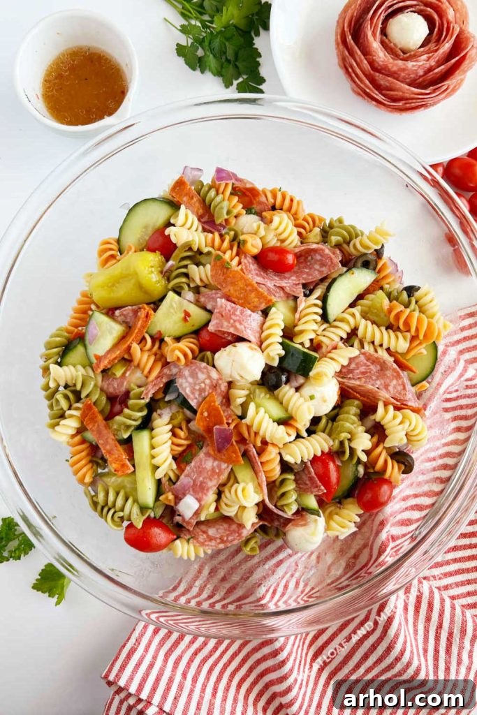 Platter of Italian pasta salad with pepperoni, rotini pasta, fresh vegetables, garnished with a pepperoni rose, ready for serving at a picnic or potluck.