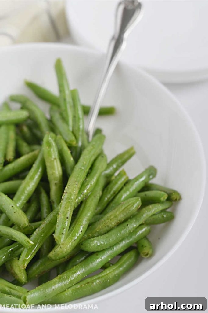 Fresh cooked green beans in a white bowl, perfectly steamed