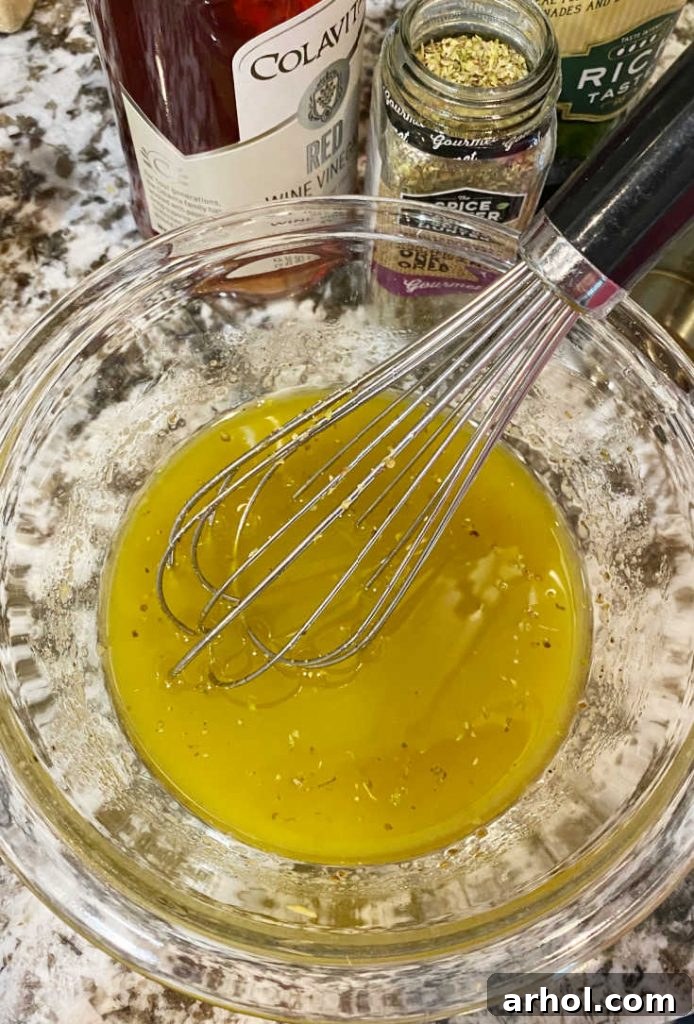 Close-up shot of red wine vinaigrette dressing being whisked in a small glass bowl, showing the emulsification process.