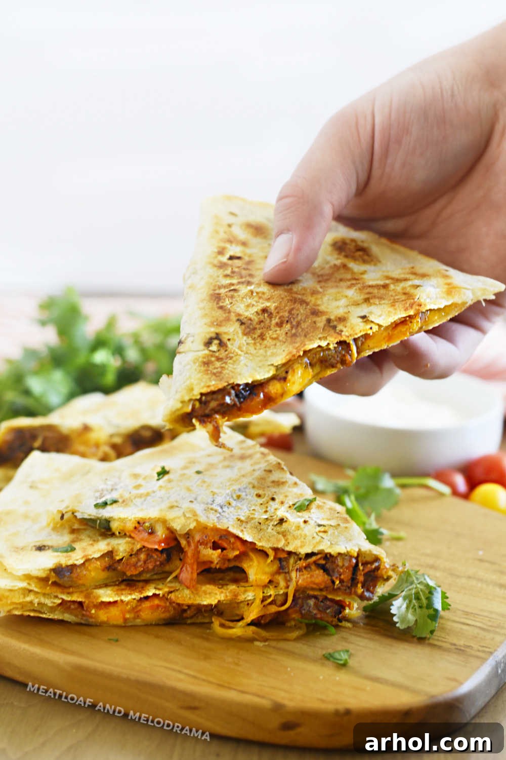Hand holding a perfectly sliced, golden-brown steak quesadilla revealing melted cheese and tender steak filling