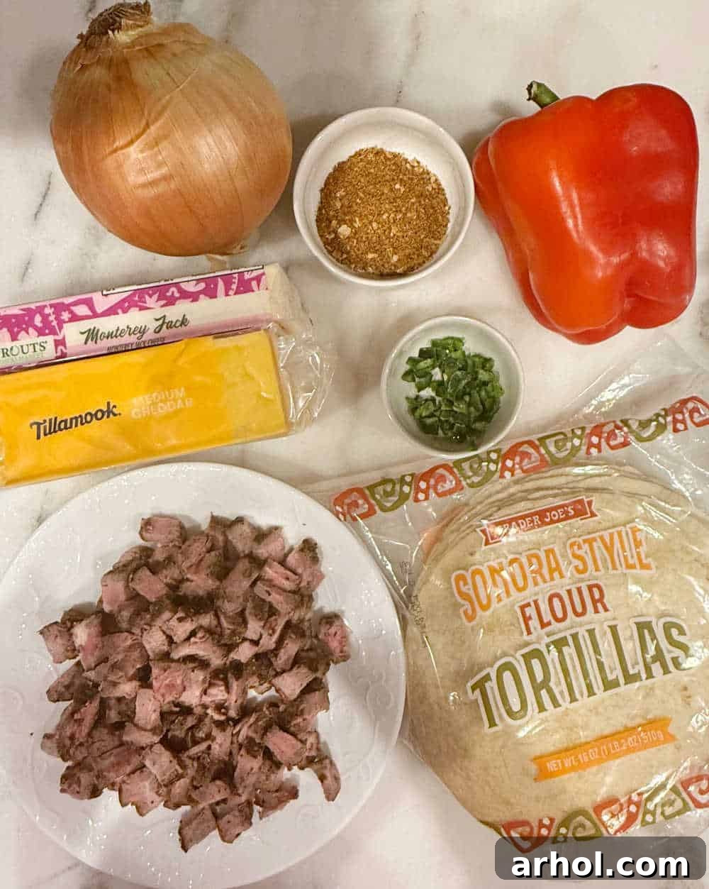 Cooked steak, assorted shredded cheeses, large flour tortillas, colorful bell peppers, onion, and taco seasoning arranged on a counter