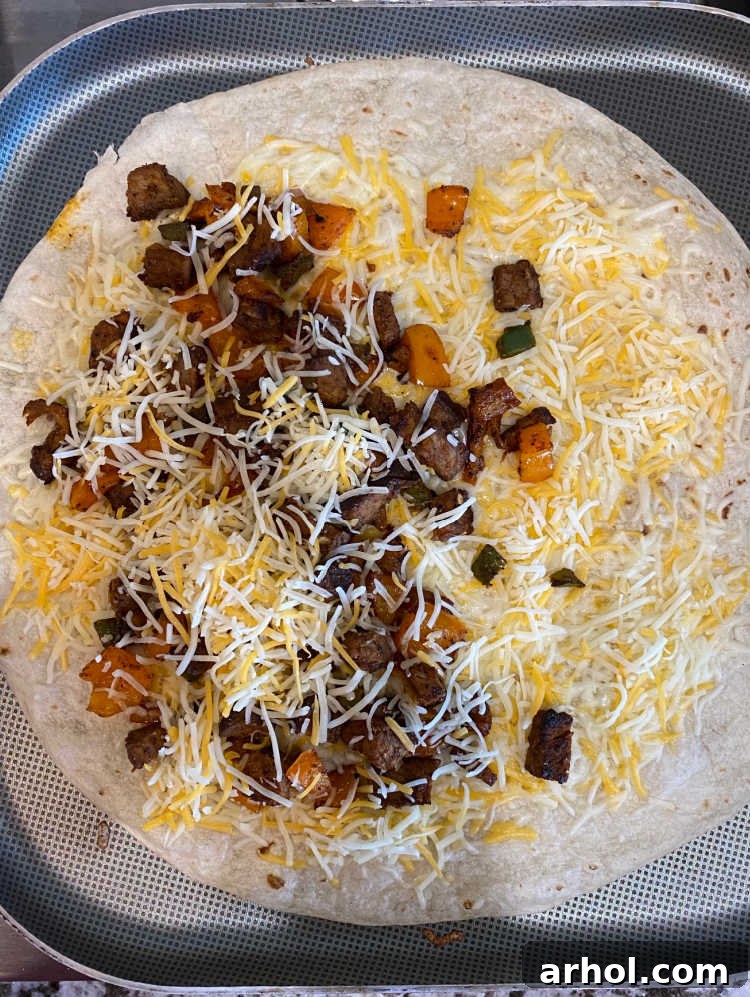 Steak and cheese filling layered on half of a warm tortilla on a griddle