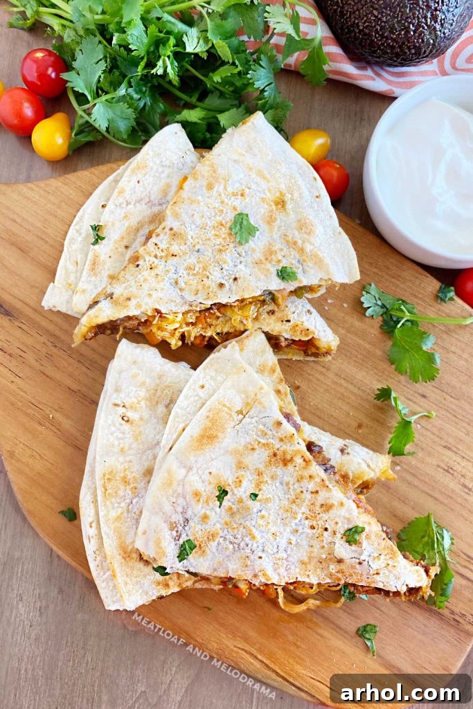 Overhead view of perfectly sliced steak quesadillas garnished with fresh cilantro on a wooden cutting board