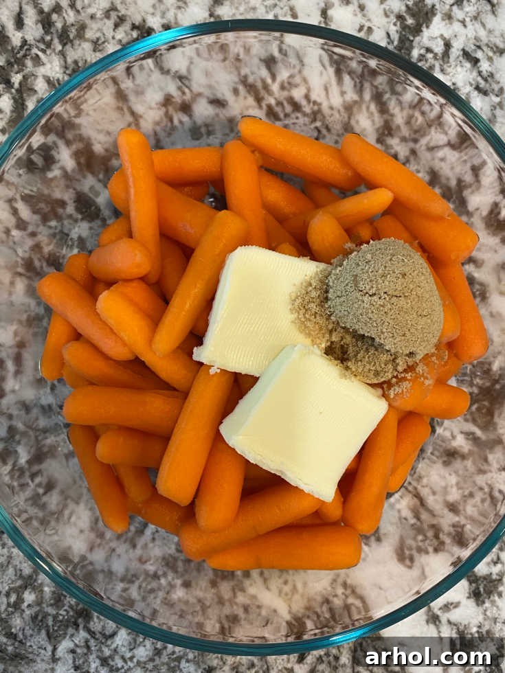 Raw baby carrots in a glass dish with pats of butter and a sprinkle of brown sugar.