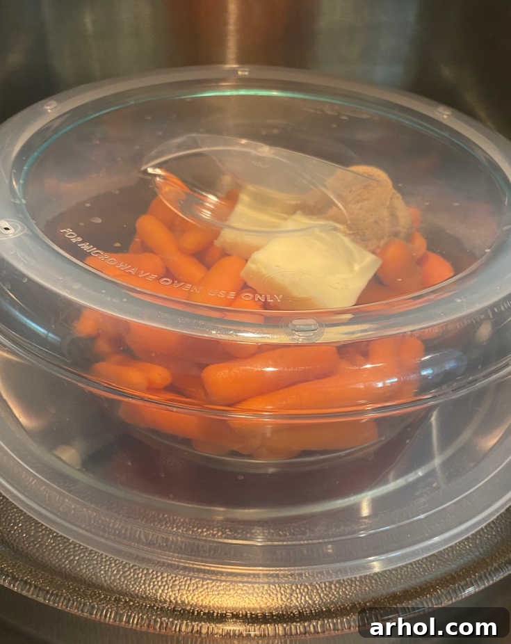 Microwave-safe dish with carrots, covered, and placed inside a microwave oven.