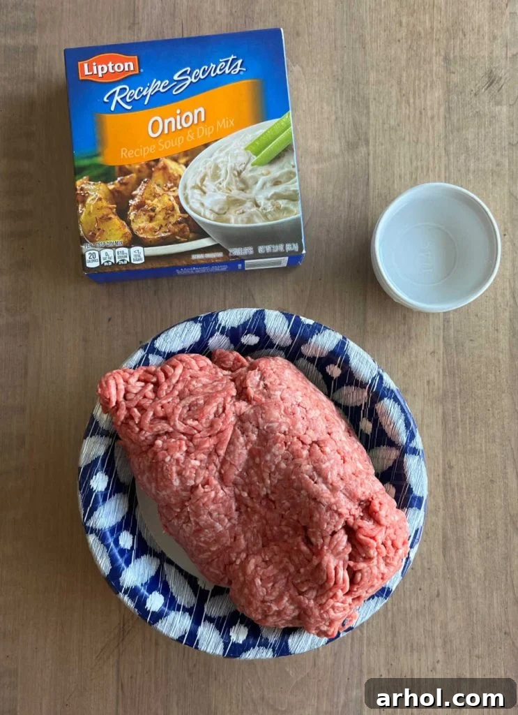 The three essential ingredients for Lipton onion soup burgers: a package of Lipton Onion Soup Mix, raw ground beef, and a measuring cup of water, all arranged on a kitchen counter.