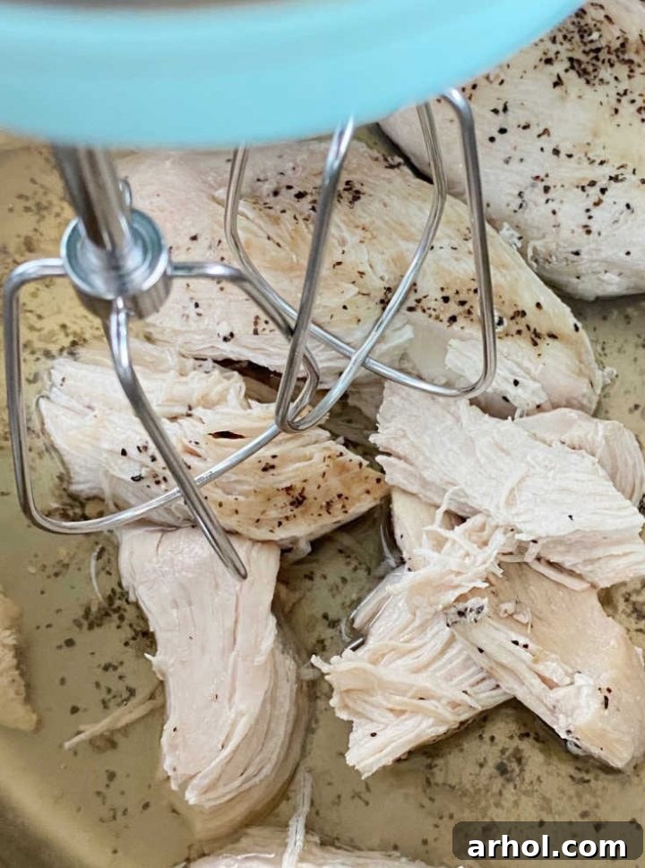 Shredding cooked chicken in the Instant Pot with an electric mixer for quick meal prep.
