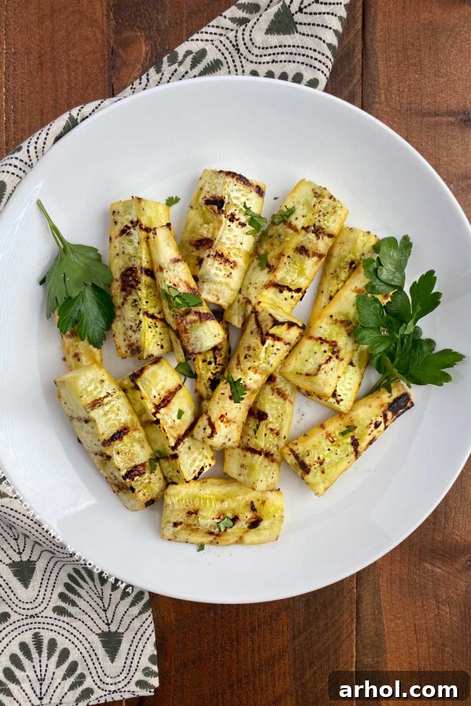 Grilled yellow summer squash spears arranged beautifully on a white platter, garnished with fresh parsley.