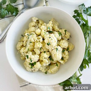 Microwave cauliflower in a white serving bowl, garnished with parsley.