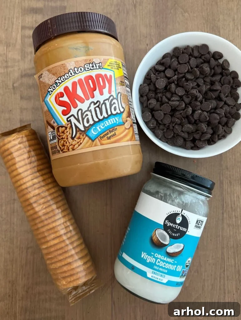 Key ingredients for chocolate peanut butter Ritz cookies: a jar of peanut butter, a bowl of chocolate chips, a stack of Ritz crackers, and a small container of coconut oil, arranged appealingly on a wooden surface.