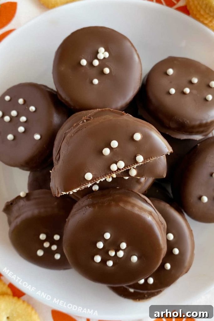 A plate generously filled with finished chocolate covered Ritz peanut butter cracker cookies, beautifully adorned with vibrant colorful sprinkles, ready to be enjoyed.