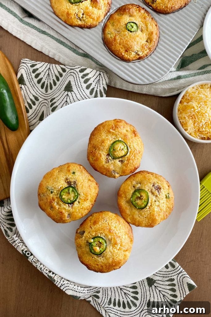 Golden brown Jalapeño Sausage Cornbread Muffins arranged beautifully on a white plate, highlighting their savory goodness with a hint of green from the peppers.