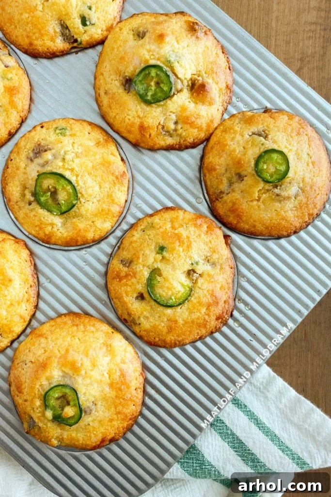 Freshly baked Jalapeño Corn Muffins still in the muffin tin, with perfectly golden brown tops, just removed from the oven.