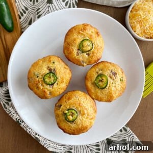 A delicious plate of Jiffy Jalapeño Sausage Cornbread Muffins, perfectly baked and garnished with a fresh jalapeño slice, enticing all who see it.